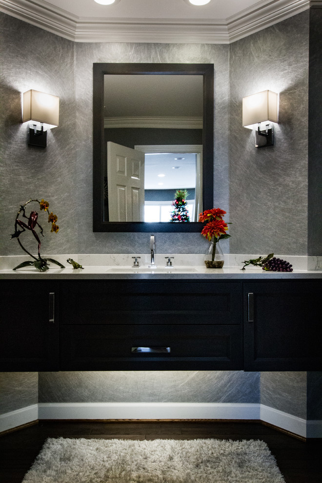 Photo of a mid-sized contemporary powder room in Detroit with flat-panel cabinets, brown cabinets, grey walls, medium hardwood floors, an undermount sink, engineered quartz benchtops, brown floor and white benchtops.