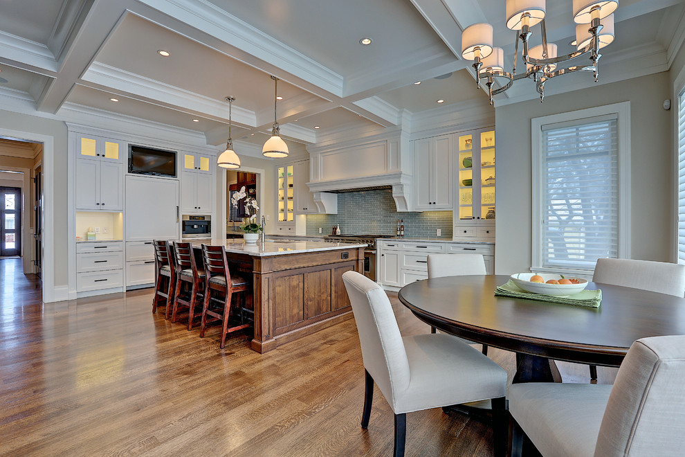 Eat-in kitchen - large transitional l-shaped medium tone wood floor eat-in kitchen idea in Calgary with an undermount sink, shaker cabinets, white cabinets, marble countertops, gray backsplash, glass tile backsplash and an island