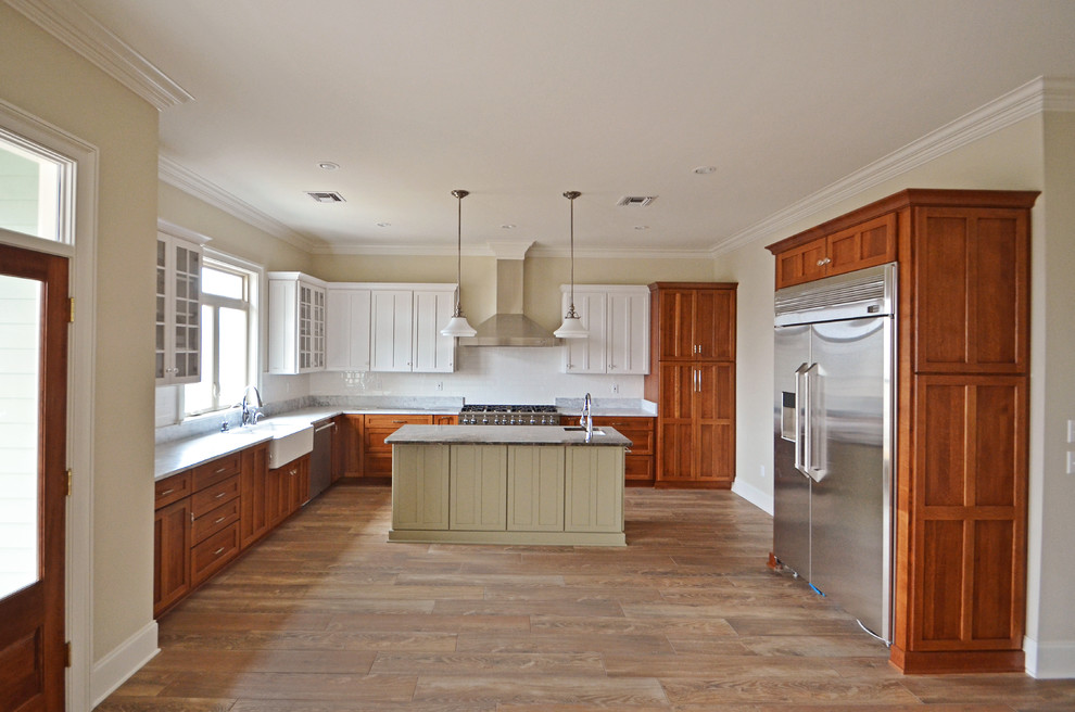 Design ideas for a mid-sized arts and crafts l-shaped open plan kitchen in New Orleans with shaker cabinets, medium wood cabinets, granite benchtops, white splashback, subway tile splashback, stainless steel appliances, with island, a farmhouse sink and medium hardwood floors.