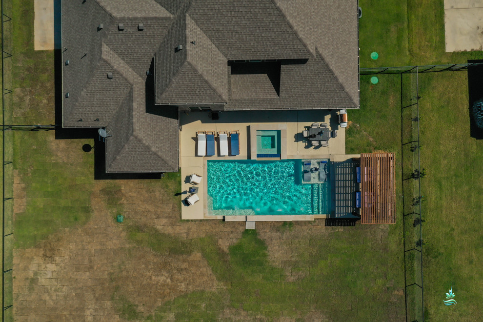 This is an example of a mid-sized country backyard rectangular pool in Dallas with a hot tub and decking.