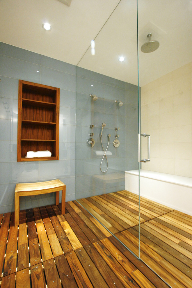Photo of a mid-sized contemporary master bathroom in Chicago with a curbless shower, a wall-mount toilet, blue tile, ceramic tile, blue walls and medium hardwood floors.
