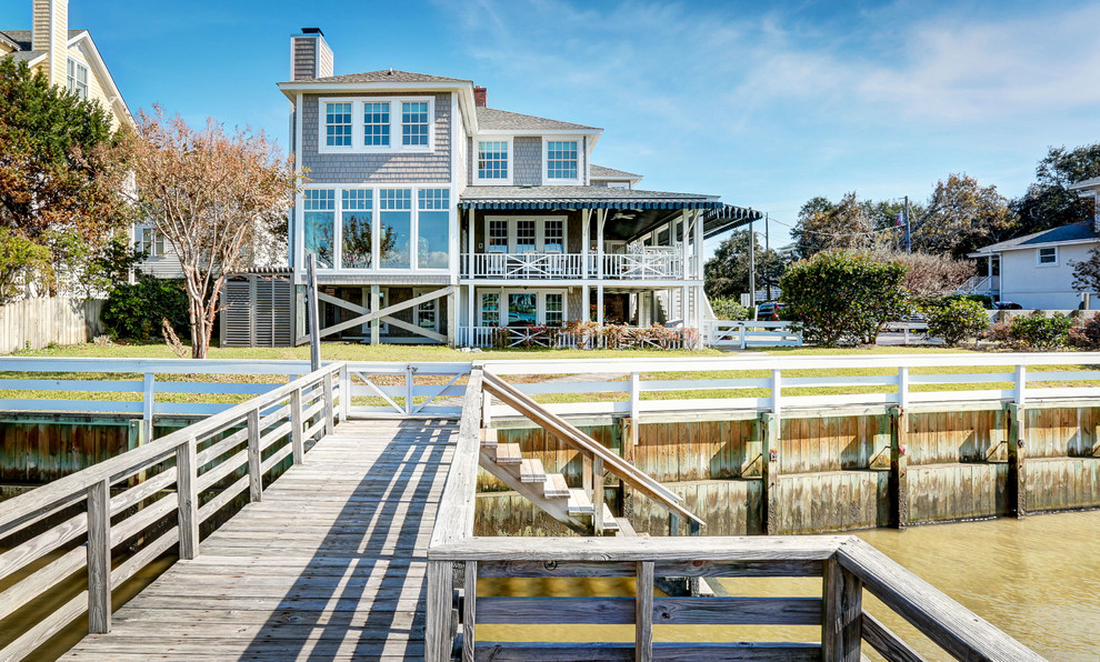 Photo of a large beach style three-storey grey exterior in Wilmington with wood siding and a flat roof.