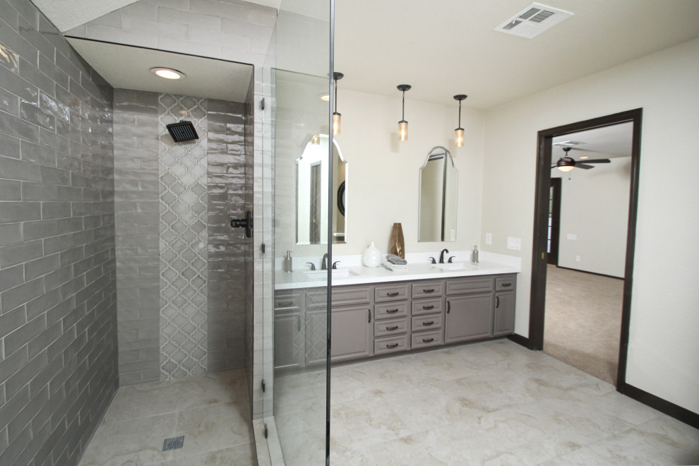 Photo of a mid-sized master bathroom in Las Vegas with raised-panel cabinets, grey cabinets, a freestanding tub, an alcove shower, gray tile, porcelain tile, beige walls, porcelain floors, an undermount sink, engineered quartz benchtops, beige floor, a hinged shower door, white benchtops, an enclosed toilet, a double vanity, a built-in vanity and vaulted.