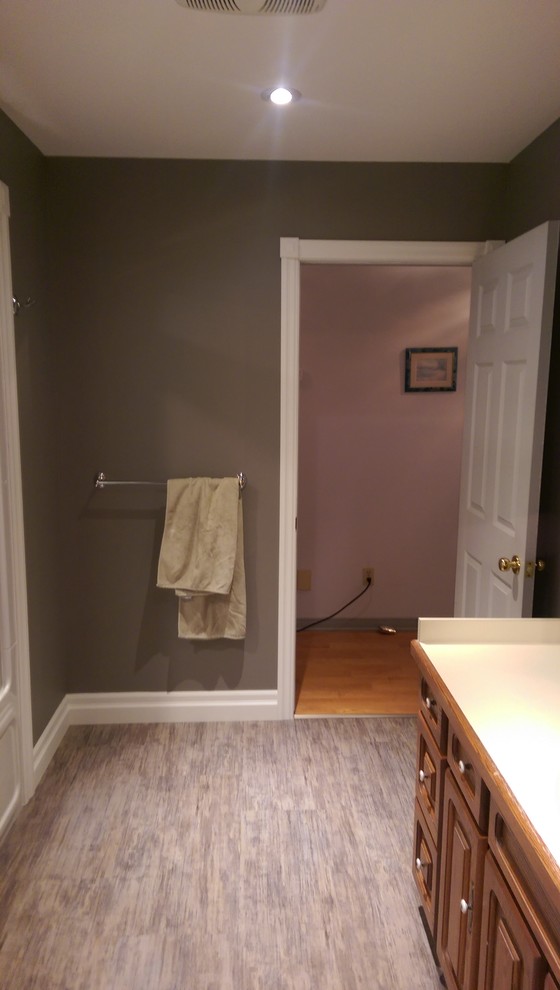 Mid-sized transitional master vinyl floor and multicolored floor alcove bathtub photo with recessed-panel cabinets, medium tone wood cabinets, a two-piece toilet, gray walls, laminate countertops and yellow countertops