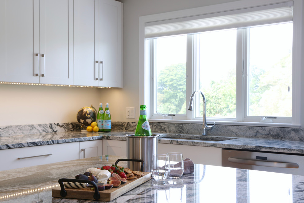 This is an example of a mid-sized transitional u-shaped eat-in kitchen in Providence with an undermount sink, shaker cabinets, white cabinets, granite benchtops, white splashback, stone slab splashback, stainless steel appliances, medium hardwood floors and with island.
