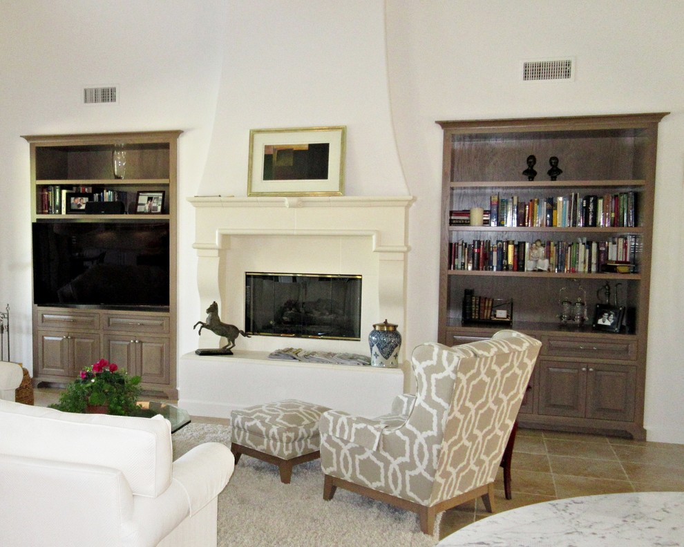 This is an example of a large transitional open concept living room in Los Angeles with a library, white walls, ceramic floors, a standard fireplace, a stone fireplace surround and a built-in media wall.