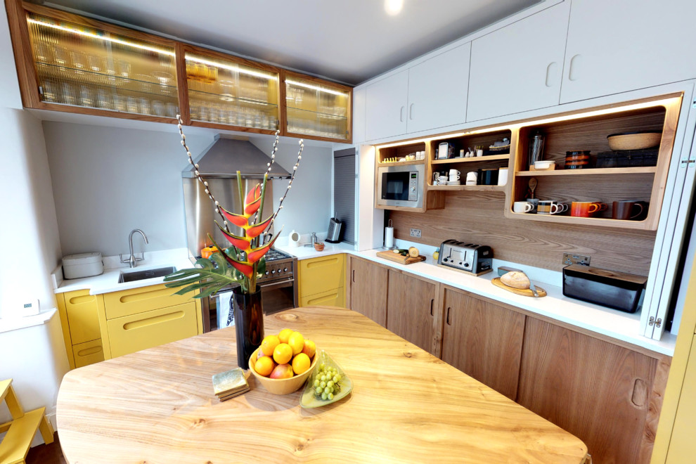 Photo of a large midcentury l-shaped eat-in kitchen in Manchester with an integrated sink, flat-panel cabinets, yellow cabinets, quartz benchtops, stainless steel appliances, porcelain floors, with island and brown floor.