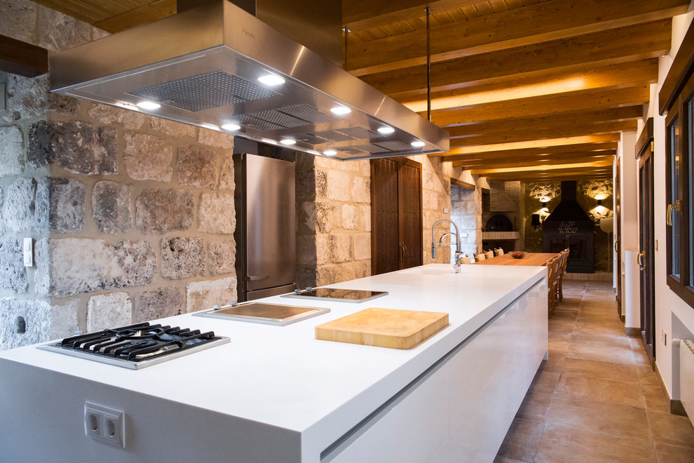This is an example of a large country single-wall eat-in kitchen in Alicante-Costa Blanca with ceramic floors, brown floor, an integrated sink, flat-panel cabinets, white cabinets, solid surface benchtops and with island.
