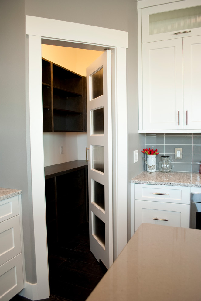 Kitchen - transitional u-shaped kitchen idea with an undermount sink, recessed-panel cabinets, white cabinets, quartz countertops, gray backsplash, stainless steel appliances and an island
