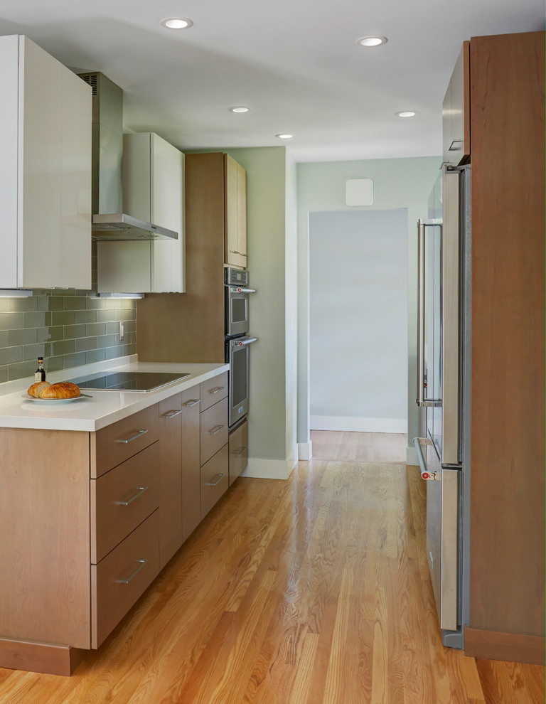 Photo of a small contemporary galley eat-in kitchen in San Francisco with brown cabinets, quartzite benchtops, green splashback, glass tile splashback, stainless steel appliances, no island and white benchtop.