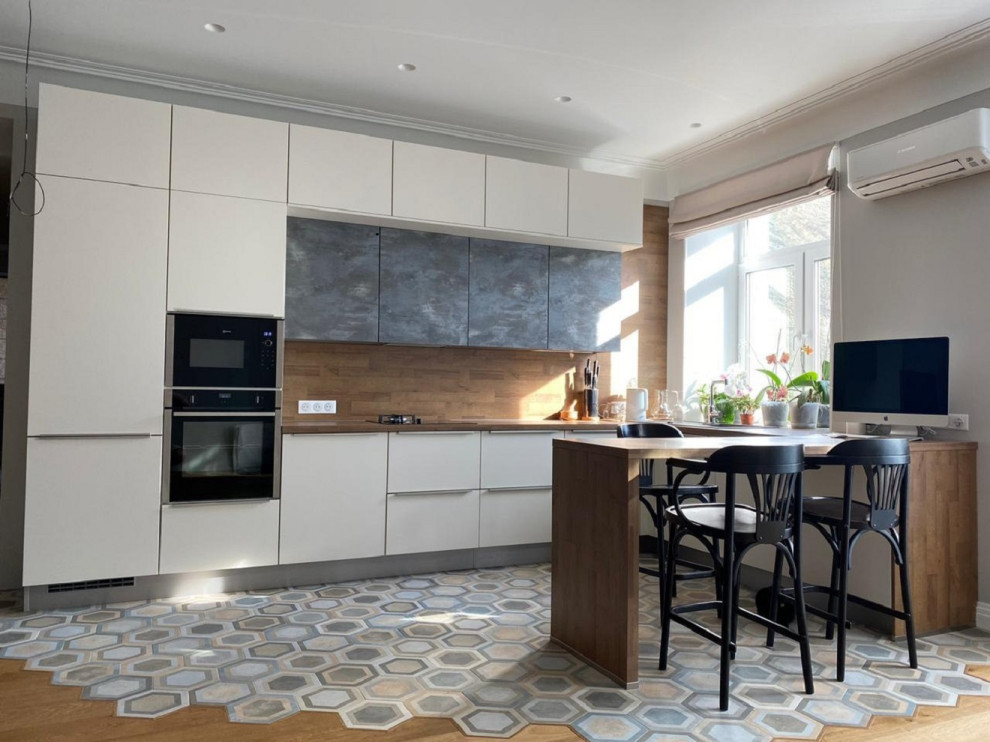 Mid-sized contemporary u-shaped open plan kitchen in Other with flat-panel cabinets, beige cabinets, laminate benchtops, brown splashback, ceramic floors, a peninsula, multi-coloured floor and brown benchtop.