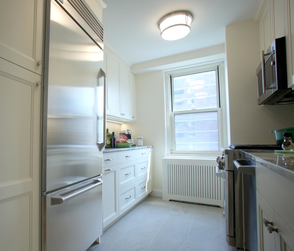 Mid-sized transitional galley separate kitchen in New York with an undermount sink, recessed-panel cabinets, white cabinets, marble benchtops, beige splashback, glass tile splashback, stainless steel appliances, ceramic floors and no island.