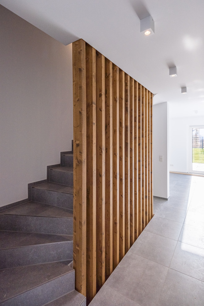 Идея дизайна: изогнутая лестница среднего размера в современном стиле с ступенями из плитки, подступенками из плитки и деревянными перилами
