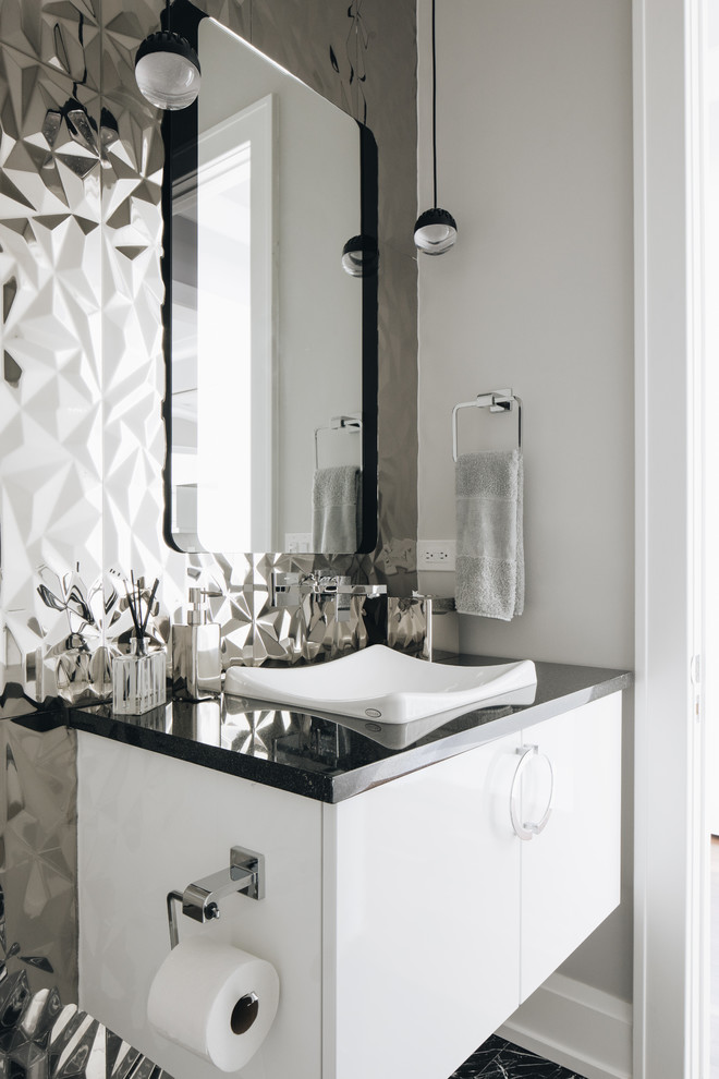 Inspiration for a small modern powder room in Chicago with flat-panel cabinets, white cabinets, a wall-mount toilet, gray tile, metal tile, grey walls, marble floors, a vessel sink, granite benchtops, black floor and white benchtops.