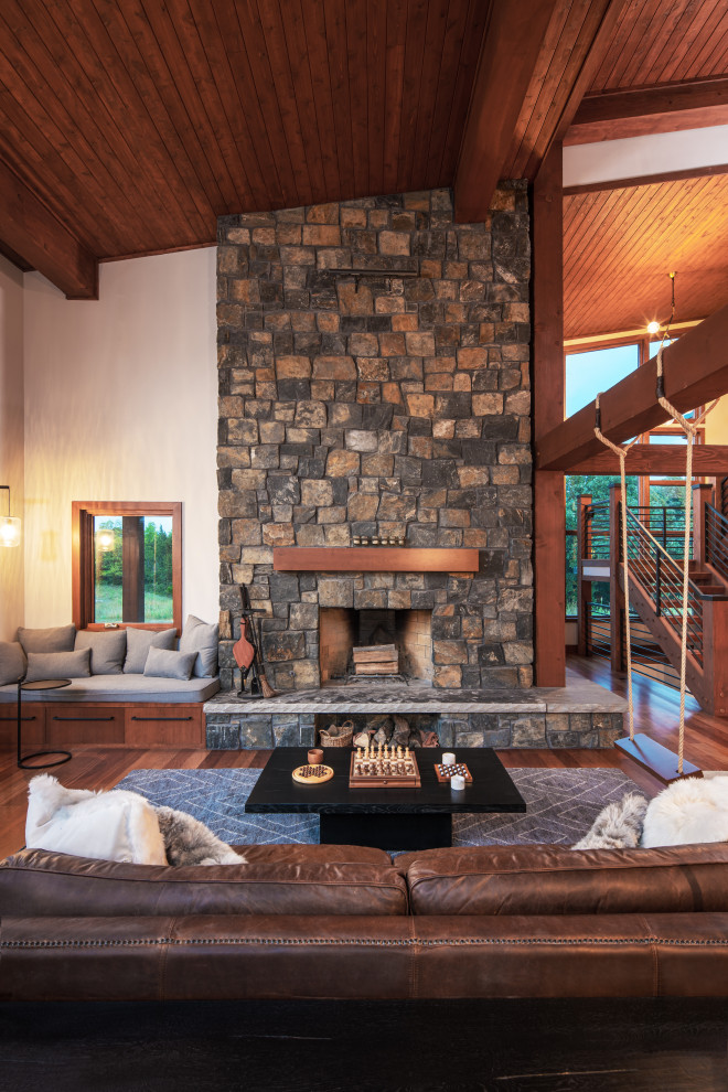 Inspiration for a medium sized rustic open plan games room in Omaha with a music area, medium hardwood flooring, a standard fireplace, a stacked stone fireplace surround, no tv, red floors and a wood ceiling.