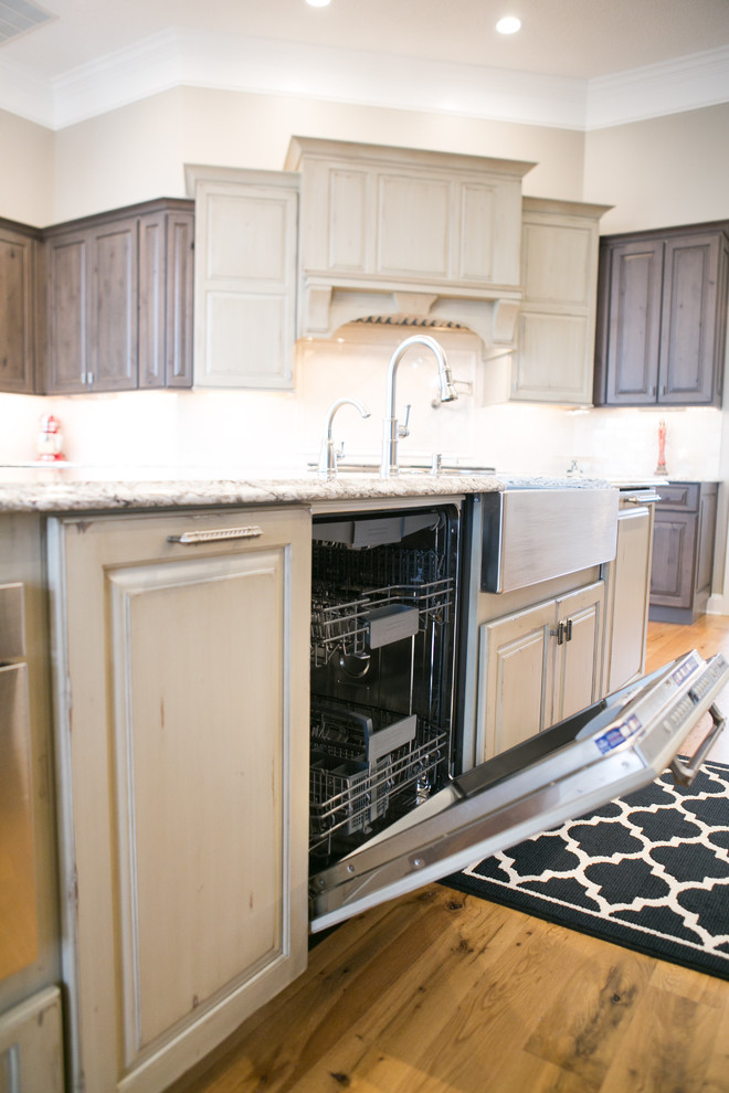 Example of a large transitional u-shaped medium tone wood floor and brown floor kitchen design in Indianapolis with a farmhouse sink, raised-panel cabinets, dark wood cabinets, granite countertops, white backsplash, subway tile backsplash, paneled appliances, an island and multicolored countertops