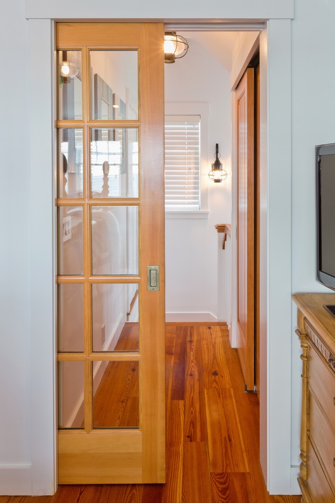 This is an example of a beach style hallway in Boston with white walls and medium hardwood floors.