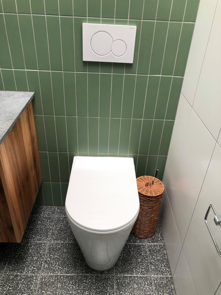 Exemple d'une petite salle de bain principale tendance avec un placard à porte plane, des portes de placard marrons, une douche ouverte, WC à poser, un carrelage vert, des carreaux de céramique, un mur vert, un sol en carrelage de céramique, un lavabo encastré, un plan de toilette en surface solide, un sol noir, un plan de toilette gris, meuble double vasque et meuble-lavabo encastré.
