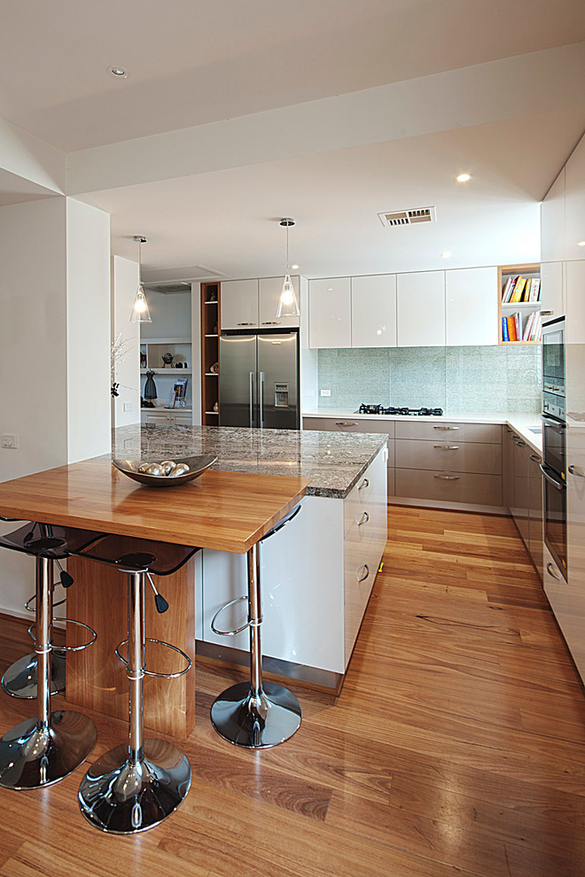 Mid-sized contemporary l-shaped separate kitchen in Melbourne with a double-bowl sink, flat-panel cabinets, grey cabinets, granite benchtops, green splashback, porcelain splashback, stainless steel appliances, with island and medium hardwood floors.