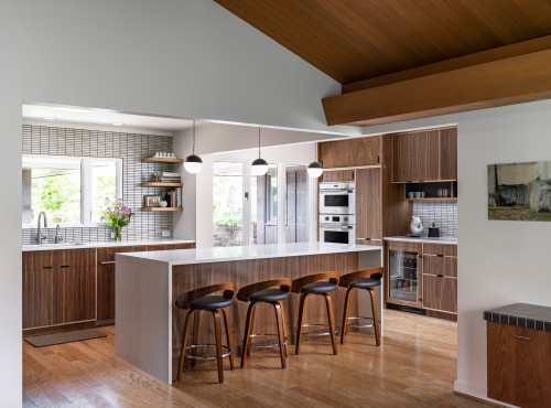 Modern kitchen with wood-grain plywood cabinets, large white island and bar stools