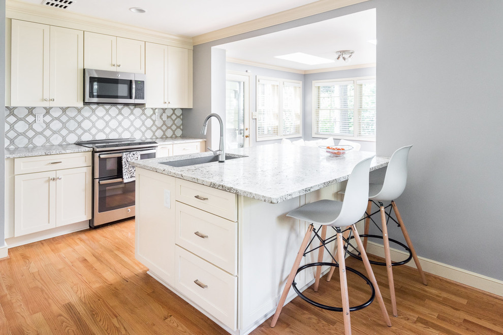 Example of a transitional medium tone wood floor kitchen design in Richmond with a drop-in sink, shaker cabinets, white cabinets, granite countertops, white backsplash, marble backsplash, stainless steel appliances and a peninsula