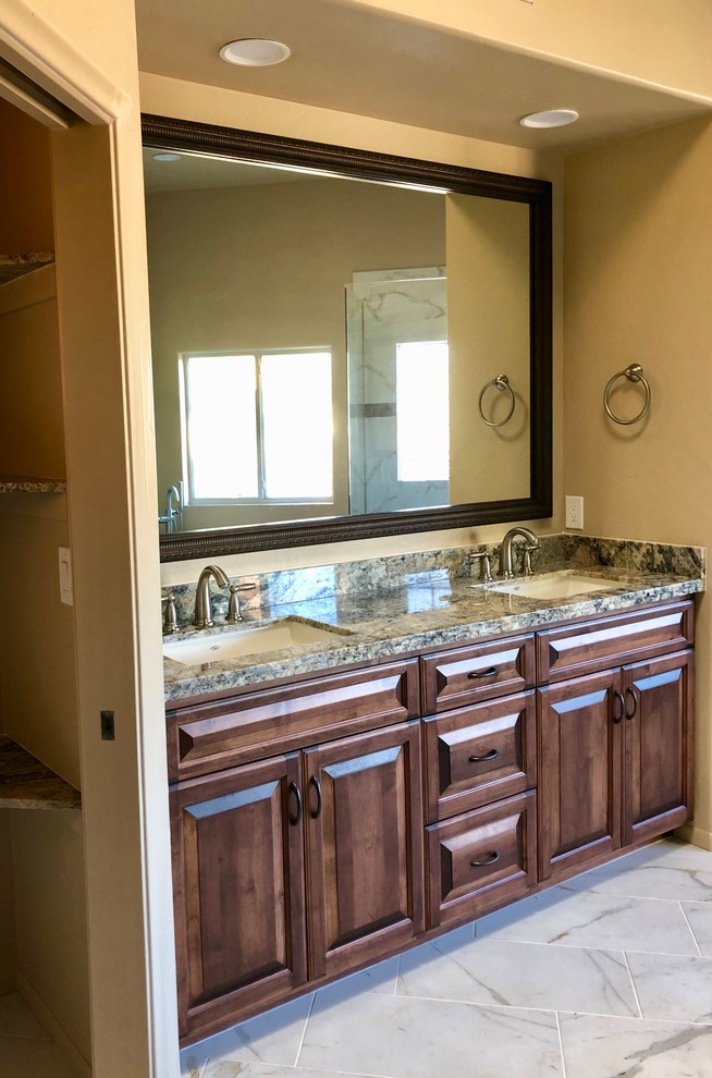 This is an example of a large traditional master bathroom in Phoenix with raised-panel cabinets, dark wood cabinets, white tile, granite benchtops, multi-coloured benchtops, a freestanding tub, a corner shower, a one-piece toilet, orange walls, an undermount sink, white floor and a hinged shower door.