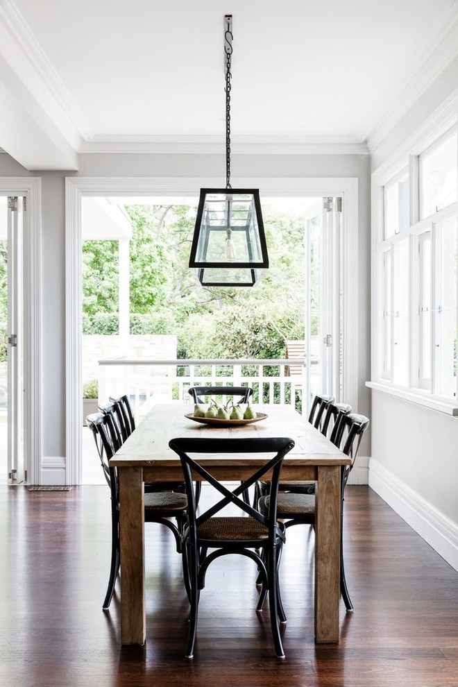 This is an example of a country dining room in Sydney with grey walls and dark hardwood floors.