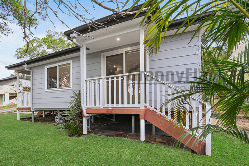 This is an example of a small beach style one-storey exterior in Sydney with wood siding and a gable roof.