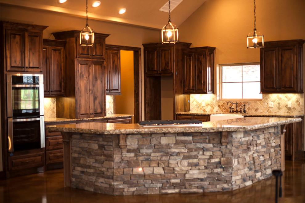 Photo of a large country l-shaped eat-in kitchen in Oklahoma City with a farmhouse sink, raised-panel cabinets, dark wood cabinets, granite benchtops, stone tile splashback, stainless steel appliances, concrete floors, with island and multi-coloured splashback.