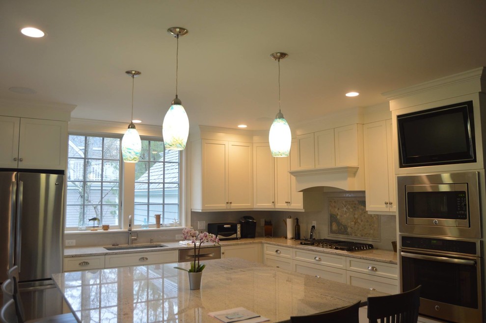 Inspiration for a large transitional l-shaped medium tone wood floor and brown floor open concept kitchen remodel in Boston with an undermount sink, shaker cabinets, white cabinets, quartzite countertops, gray backsplash, stainless steel appliances and an island