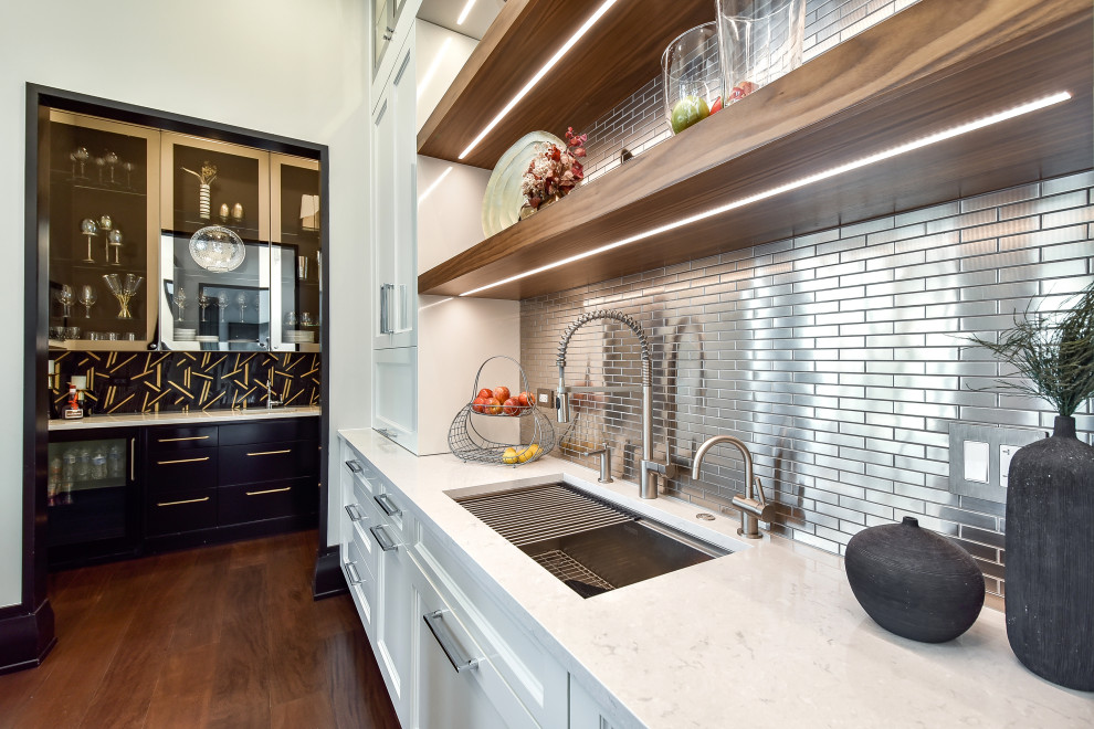 Design ideas for a large modern kitchen in Chicago with a farmhouse sink, recessed-panel cabinets, white cabinets, tile benchtops, metallic splashback, metal splashback, white appliances, dark hardwood floors, multiple islands, brown floor, white benchtop and wood.