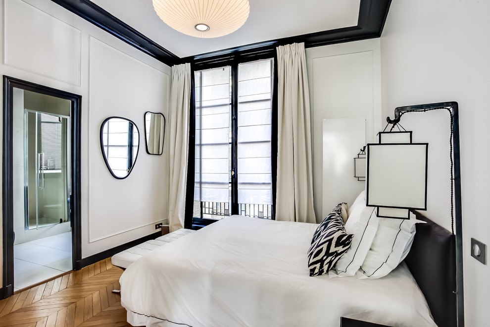 This is an example of a mid-sized contemporary master bedroom in Paris with white walls, medium hardwood floors and no fireplace.