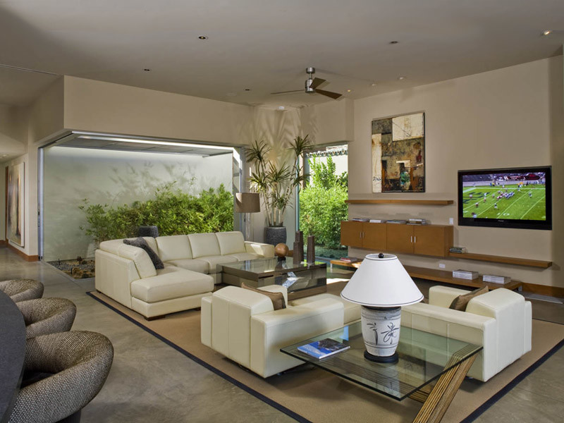 Photo of a modern open concept family room in Orange County with beige walls, concrete floors, no fireplace and a wall-mounted tv.