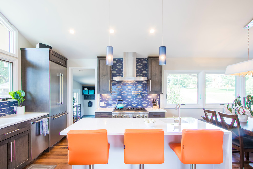 Inspiration for a transitional l-shaped eat-in kitchen in Denver with an undermount sink, shaker cabinets, medium wood cabinets, quartzite benchtops, blue splashback, stainless steel appliances, medium hardwood floors, with island, brown floor and white benchtop.