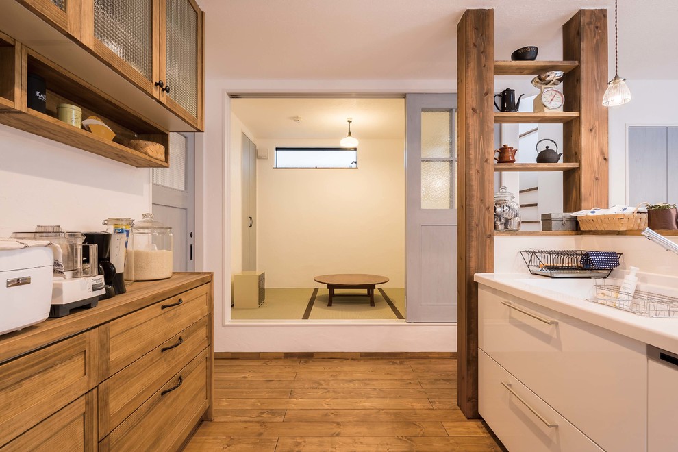 This is an example of an asian kitchen in Tokyo Suburbs with flat-panel cabinets, medium wood cabinets, medium hardwood floors, with island and brown floor.