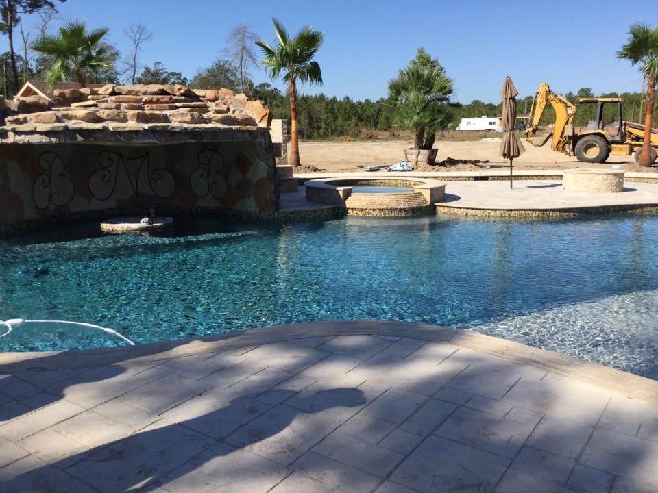 Photo of an expansive traditional backyard custom-shaped pool in Houston with a hot tub and stamped concrete.