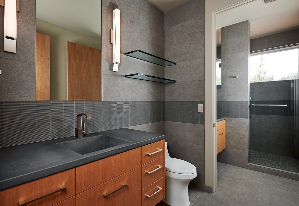 Inspiration for a mid-sized contemporary master bathroom in Other with concrete benchtops, flat-panel cabinets, brown cabinets, gray tile, grey walls, an integrated sink, grey floor, a hinged shower door and grey benchtops.