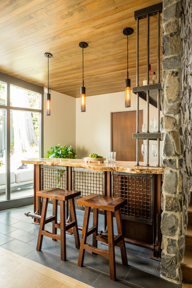 This is an example of a country seated home bar in Seattle with open cabinets, wood benchtops and grey floor.