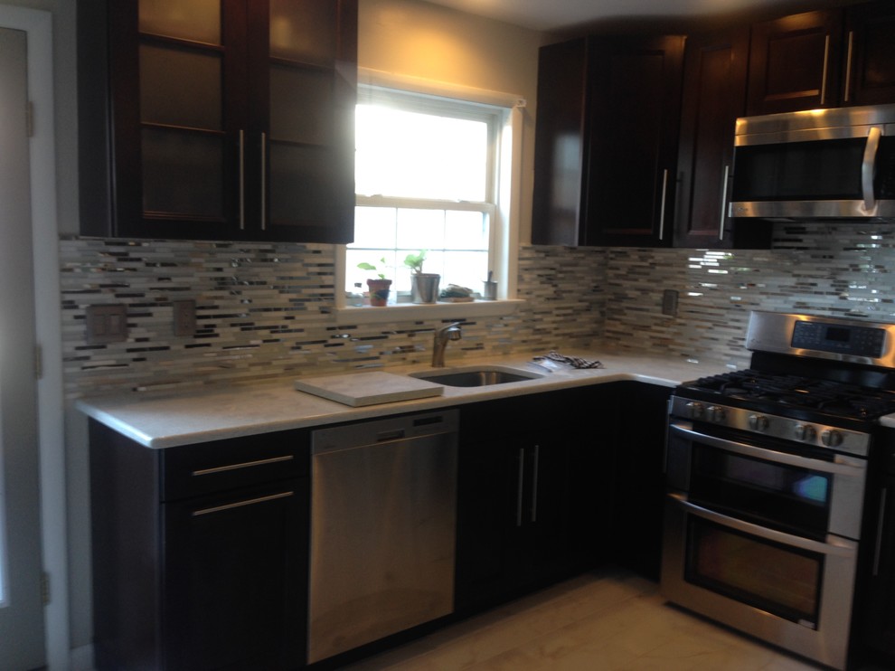 This is an example of a large transitional u-shaped eat-in kitchen in Wilmington with an undermount sink, recessed-panel cabinets, dark wood cabinets, quartz benchtops, white splashback, mosaic tile splashback, stainless steel appliances, ceramic floors, no island and beige floor.