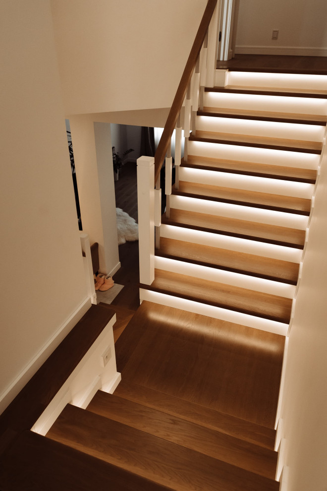 Idée de décoration pour un grand escalier courbe design avec des marches en bois, des contremarches en bois, un garde-corps en métal et un mur en parement de brique.