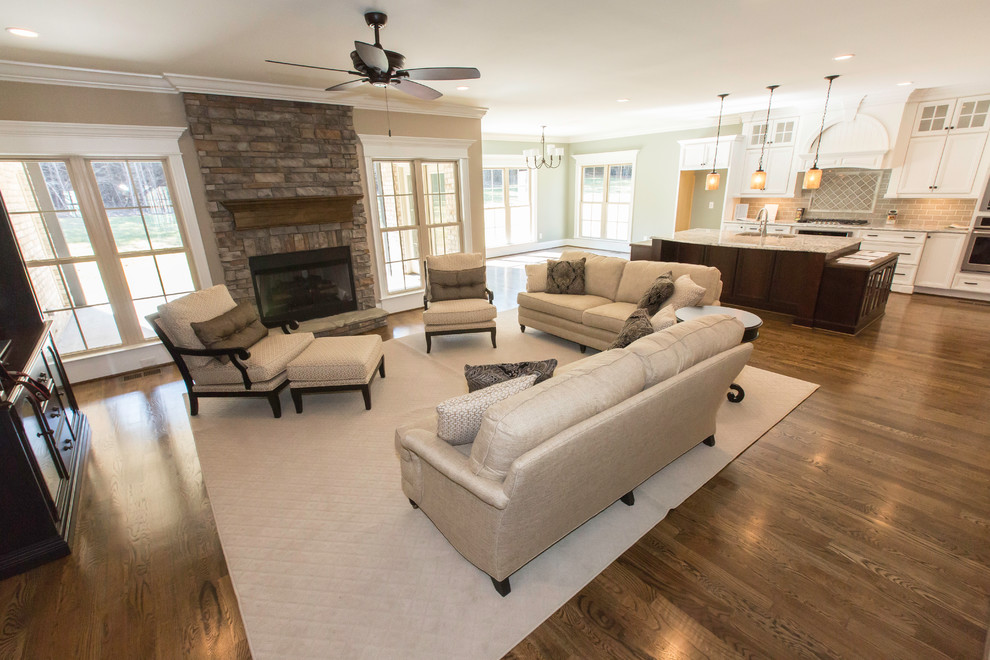 This is an example of a mid-sized transitional open concept family room in Raleigh with beige walls, medium hardwood floors, a standard fireplace and a stone fireplace surround.