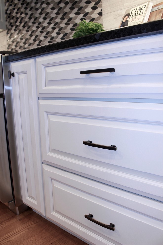 Inspiration for a large transitional u-shaped medium tone wood floor and brown floor eat-in kitchen remodel in Cincinnati with a single-bowl sink, raised-panel cabinets, white cabinets, granite countertops, beige backsplash, porcelain backsplash, stainless steel appliances and an island
