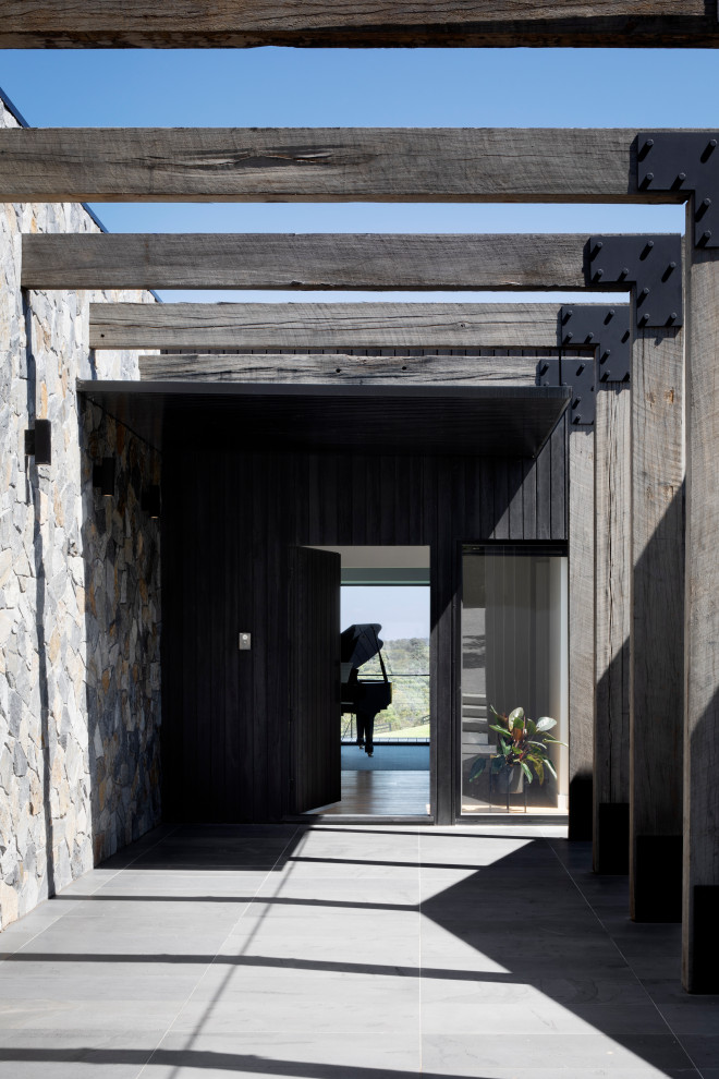 Idee per un'ampia porta d'ingresso minimal con pareti nere, una porta a pivot e una porta nera