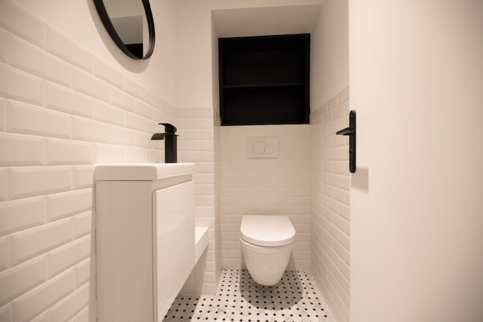 Идея дизайна: туалет среднего размера в современном стиле с плоскими фасадами, белыми фасадами, инсталляцией, белой плиткой, плиткой кабанчик, белыми стенами, полом из керамической плитки, подвесной раковиной, белым полом, белой столешницей и подвесной тумбой