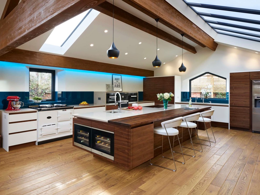 Design ideas for a large contemporary eat-in kitchen in Buckinghamshire with with island, blue splashback, stainless steel appliances, light hardwood floors, brown floor and flat-panel cabinets.
