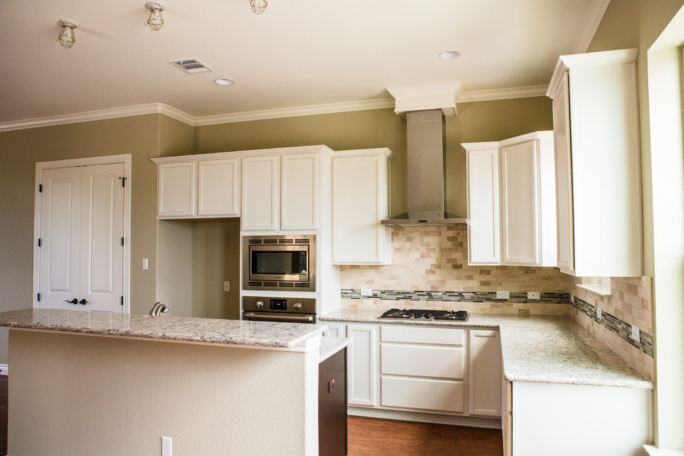 Inspiration for a mid-sized transitional l-shaped medium tone wood floor eat-in kitchen remodel in Austin with an undermount sink, recessed-panel cabinets, white cabinets, granite countertops, beige backsplash, stone tile backsplash, stainless steel appliances and an island