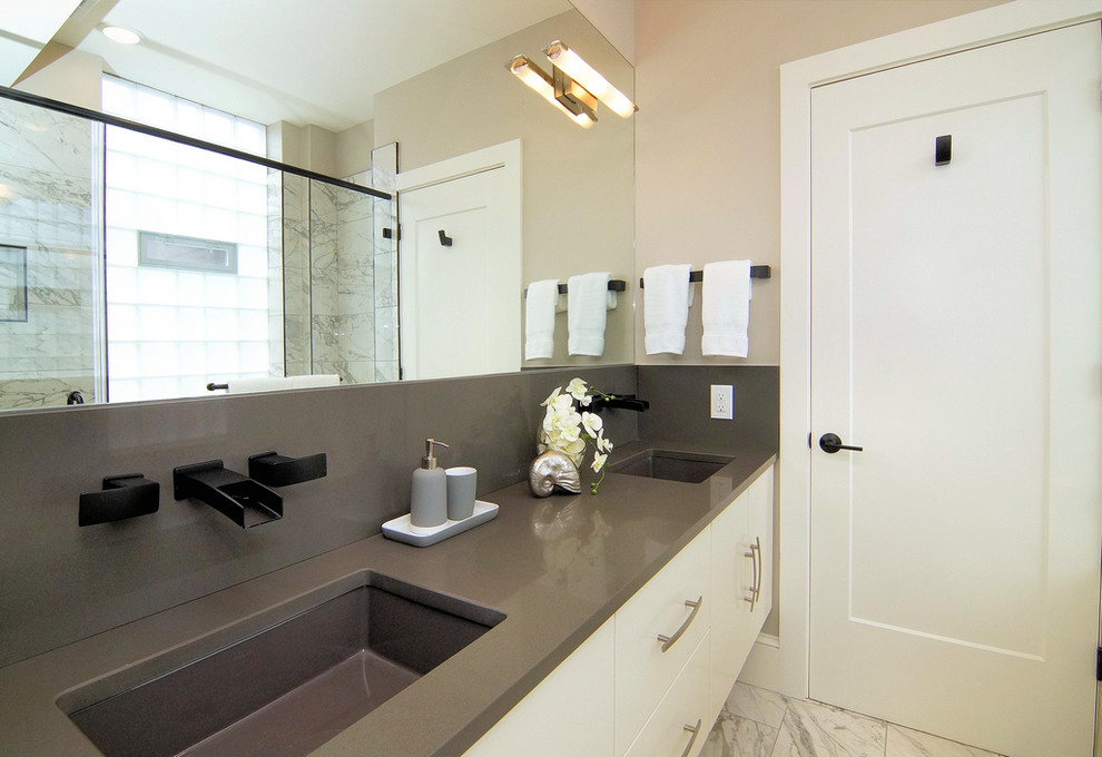 This is an example of a large asian master wet room bathroom in Cincinnati with flat-panel cabinets, brown cabinets, a two-piece toilet, multi-coloured tile, beige walls, a hinged shower door, marble, marble floors, solid surface benchtops, an undermount sink and grey floor.
