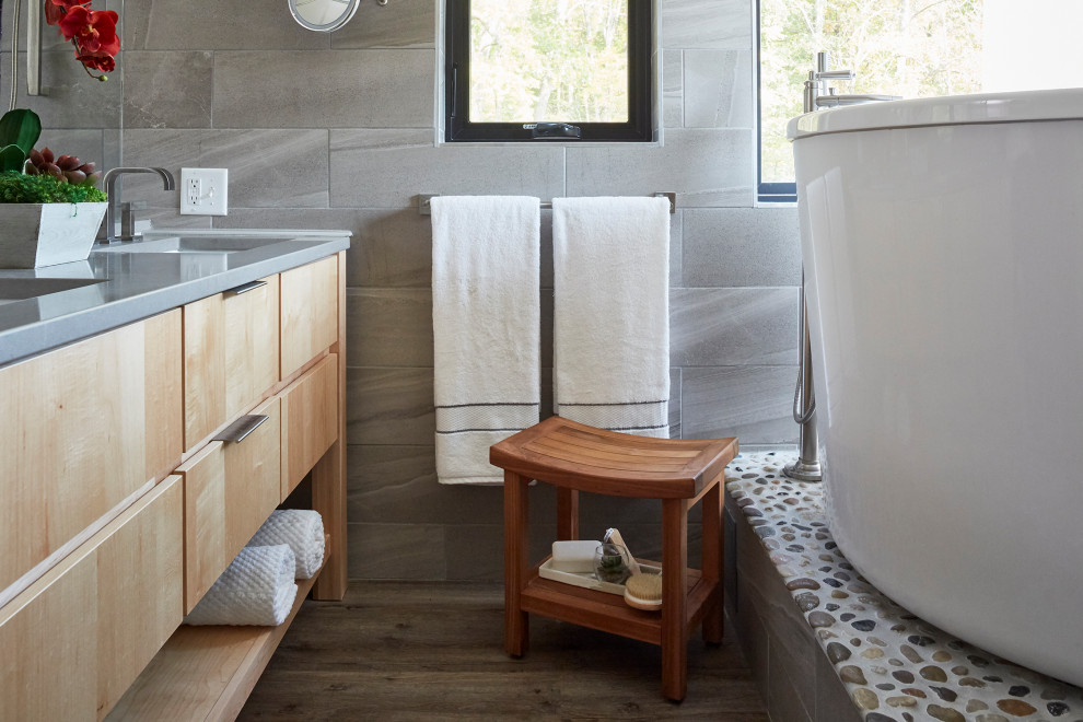 Design ideas for a small asian master bathroom in DC Metro with furniture-like cabinets, grey cabinets, a japanese tub, an open shower, gray tile, porcelain tile, white walls, medium hardwood floors, engineered quartz benchtops, brown floor, a hinged shower door and grey benchtops.