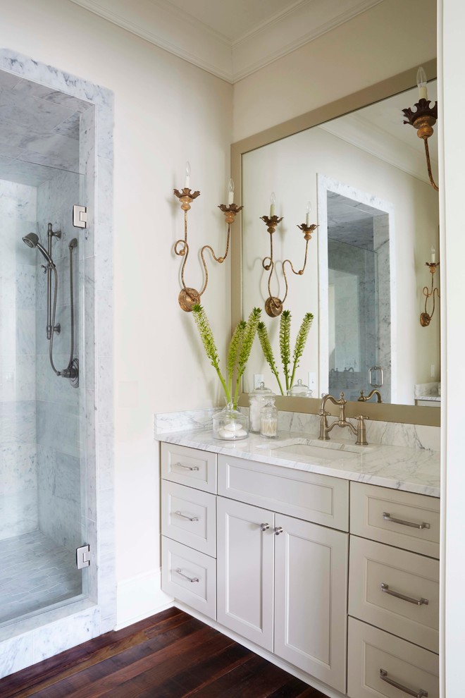 Inspiration for a mid-sized traditional bathroom in Birmingham with an undermount sink, recessed-panel cabinets, beige cabinets, gray tile, beige walls, dark hardwood floors, an alcove shower and marble benchtops.