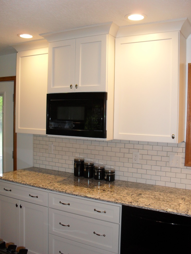 Large transitional medium tone wood floor open concept kitchen photo with white cabinets, white backsplash, black appliances, an island, recessed-panel cabinets, a farmhouse sink and subway tile backsplash